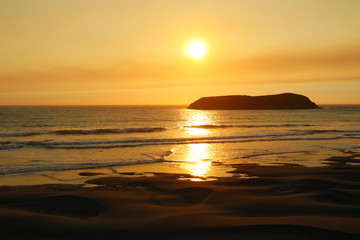 Fototapeta na wymiar Red gold. Rays of the rising sun over the ocean. Sandy beach has orange color