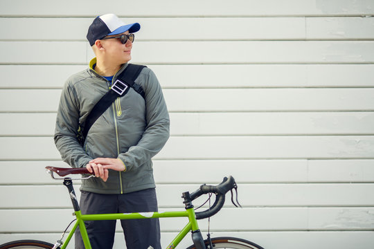 Image of young man with green bike against gray wall