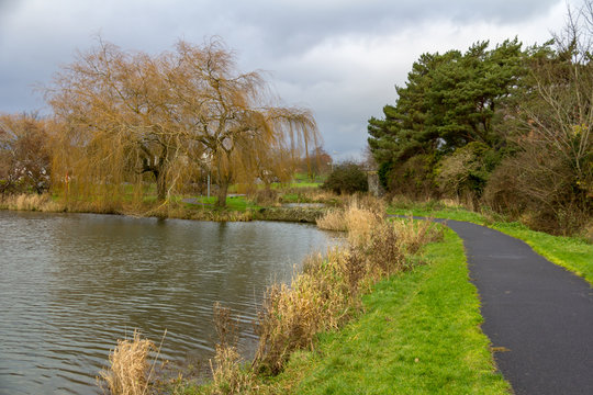 A curved path leads along the shore of a small lake in Naas Park in Ireland