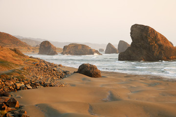 Fototapeta na wymiar View of the sandy beach and rocks during sunset in the Pacific Ocean