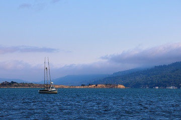 Fototapeta premium Beautiful view of the ocean and the mountains with a small yacht