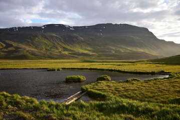 Wonderful Icelandic landscape near the hot pot Grettislaug on peninsula Skagi with a mountain and a pond.