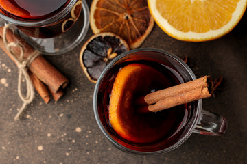 Fototapeta premium Hot mulled wine with cinnamon and orange in glass cups close-up on a dark background. View from above. Christmas. new Year.