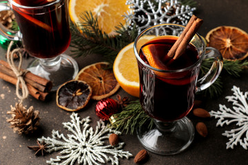 Hot mulled wine with cinnamon and orange in glass cups and Christmas decorations on a dark...