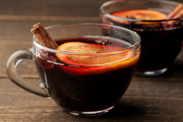Hot mulled wine with cinnamon and orange in glass cups against a dark background. Christmas. new...