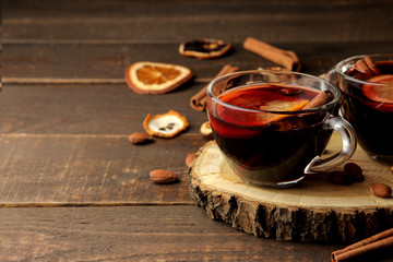 Hot mulled wine with cinnamon and orange in glass cups against a dark background. Christmas. new...