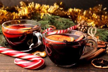 Hot mulled wine with cinnamon and orange in glass cups and Christmas decorations on a dark background. Christmas. new Year.