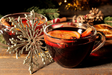 Hot mulled wine with cinnamon and orange in glass cups and Christmas decorations on a dark background. Christmas. new Year.