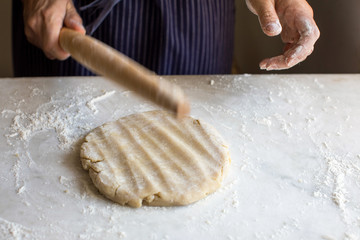 Close up of man beating dough with rolling pin