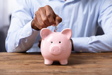 Man Inserting Coin In Piggybank