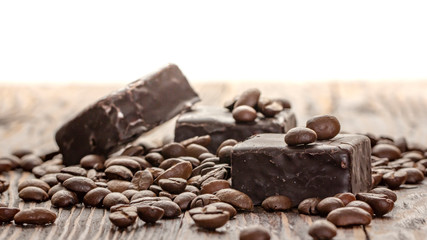 Chocolates and coffee seeds on wooden background