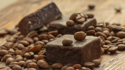 Chocolates and coffee seeds on wooden background