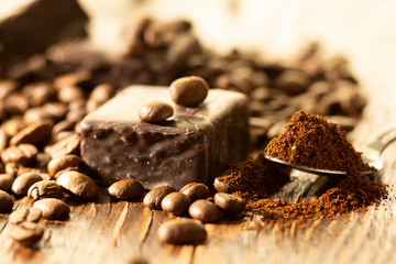 Chocolates and coffee seeds on wooden background