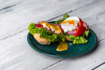 healthy and tasty sandwich with salami, peppers, purple onion, lettuce and poached egg