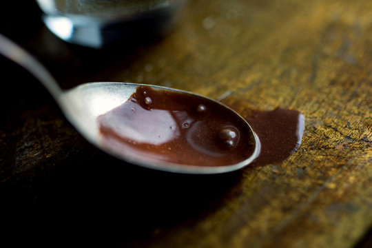 Close up of chocolate syrup spilling from spoon