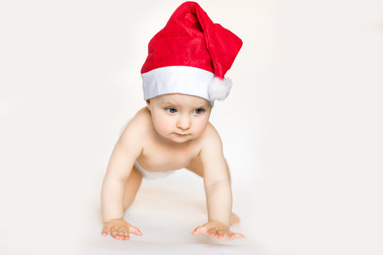 Little baby in red cap of Santa Claus celebrates Christmas. Christmas photo of infant in red cap. New Year's holidays.