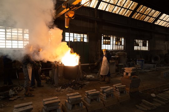 Workers molting metal in foundry workshop