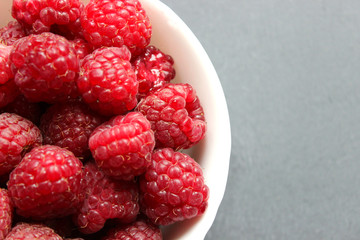 White plate with raspberry berries isolated on white background close-up.