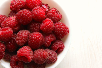 White plate with raspberry berries isolated on white background close-up.