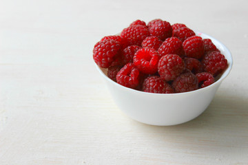 White plate with raspberry berries isolated on white background close-up.