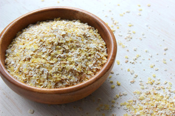 Oat flakes in a wooden bowl are insulated on a wooden table. Healthy food, vegetarianism, healthy lifestyle, diet. Copy space.