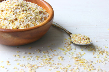 Oat flakes in a wooden bowl are insulated on a wooden table. Healthy food, vegetarianism, healthy lifestyle, diet. Copy space.