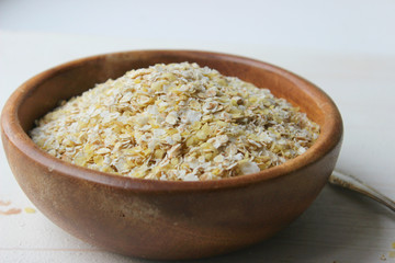Oat flakes in a wooden bowl are insulated on a wooden table. Healthy food, vegetarianism, healthy lifestyle, diet. Copy space.