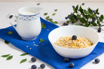 Healthy breakfast. Oatmeal with blueberries, milk jug with milk on a blue napkin on a light background