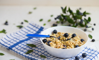 Healthy breakfast. Oatmeal with blueberries, a teaspoon with cereal and berry, light wooden background