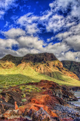 Clouds in blue sky and green fields with mountains on sunny day, north-west coast of Tenerife near Punto Teno Lighthouse, Canaria