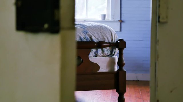 Smooth left to right dolly shot that reveals a vintage wooden bed being bounced and shaking suggestively from activity on the bed.