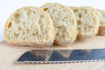 Fresh bread on a wooden kitchen board. A slice of bread smeared with butter.