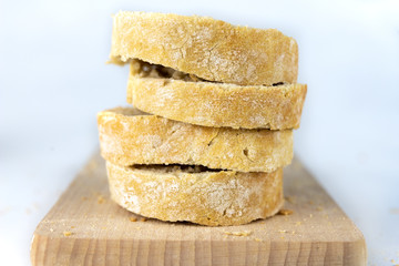 Fresh bread on a wooden kitchen board. A slice of bread smeared with butter.