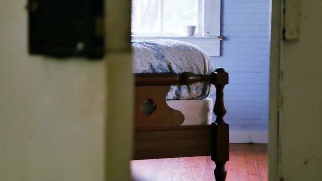 Smooth left to right dolly shot that reveals a vintage wooden bed being bounced and shaking suggestively from activity on the bed.