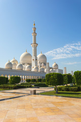 Fototapeta na wymiar Sheikh Zayed Mosque - Abu Dhabi, United Arab Emirates. Beautiful white Grand Mosque view from exerior of one of the 4 minarets and part of the garden.