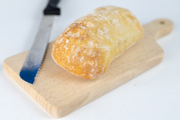 Fresh bread on a wooden kitchen board. A slice of bread smeared with butter.
