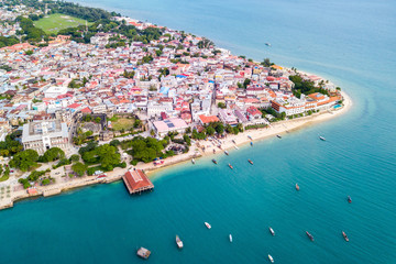 Stone Town, old colonial center of Zanzibar City. House of Wonders. Old Fort. Azure sea and stunning yellow beaches. Unguja island, Tanzania. Aerial.