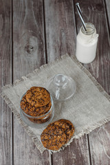 Fototapeta na wymiar Glass with fresh milk and homemade chocolate chips cookies over a wooden table. 