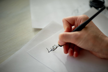 A woman's hand writes with ink, a fountain pen. Writing. The creative process of creating a work