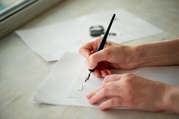 A woman's hand writes with ink, a fountain pen. Writing. The creative process of creating a work