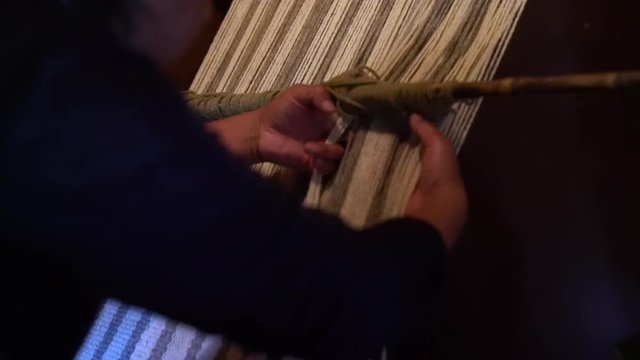 A pehuenche woman weaving a natural woolen horse blanket. Trapa Trapa Alto Biobio. Chile. Flat plane