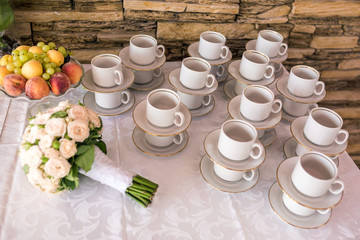View of the served for decorated table with tea set cups fruits and wedding bouquet