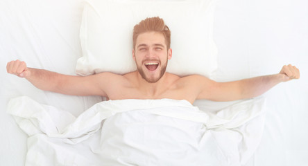 top view. happy man waking up in a comfortable bed