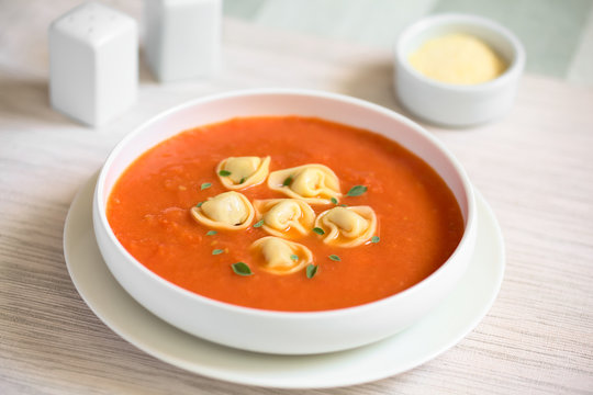 Homemade fresh cream of tomato soup with tortellini garnished with fresh oregano leaves, photographed with natural light (Selective Focus, Focus in the middle of the soup)