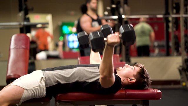 Closeup side shot of teen bodybuilder doing getting onto a bench and doing lying triceps pullover or presses.dumbbell chest fly
