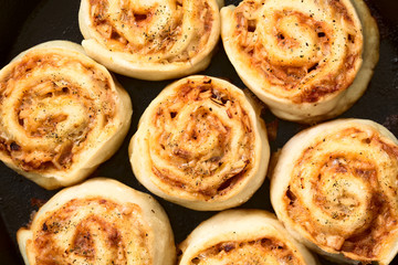 Homemade pizza rolls or pinwheels filled with ham, onion, tomato sauce and cheese, photographed overhead with natural light (Selective Focus, Focus on the top of the rolls)