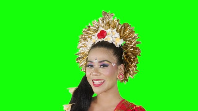 Closeup of pretty balinese dancer smiling at the camera with traditional costume and accessories in the studio. Shot in 4k resolution with green screen background