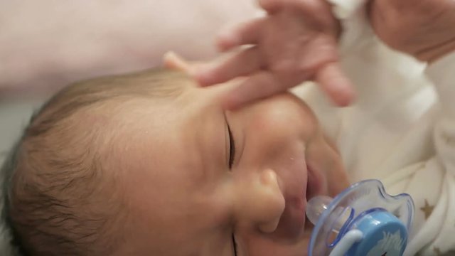 Close-up portrait of a crying newborn baby in bed.