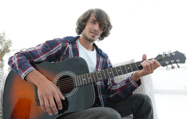 Fototapeta premium guy sings a song and plays guitar sitting on the couch.
