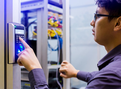 Asian young man press the button of electronic control machine with finger scan to access the door of control room or data center.